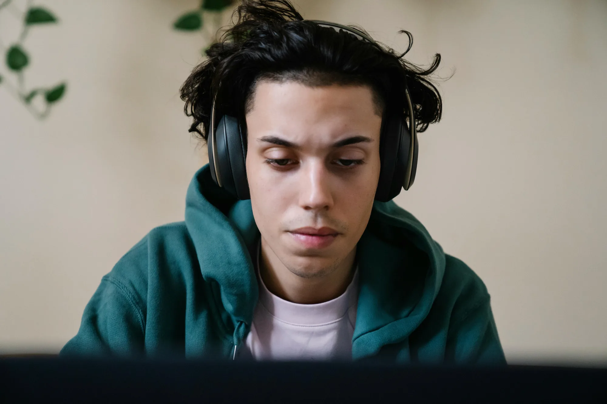 Young man in headphones focused on a laptop, working through an online course