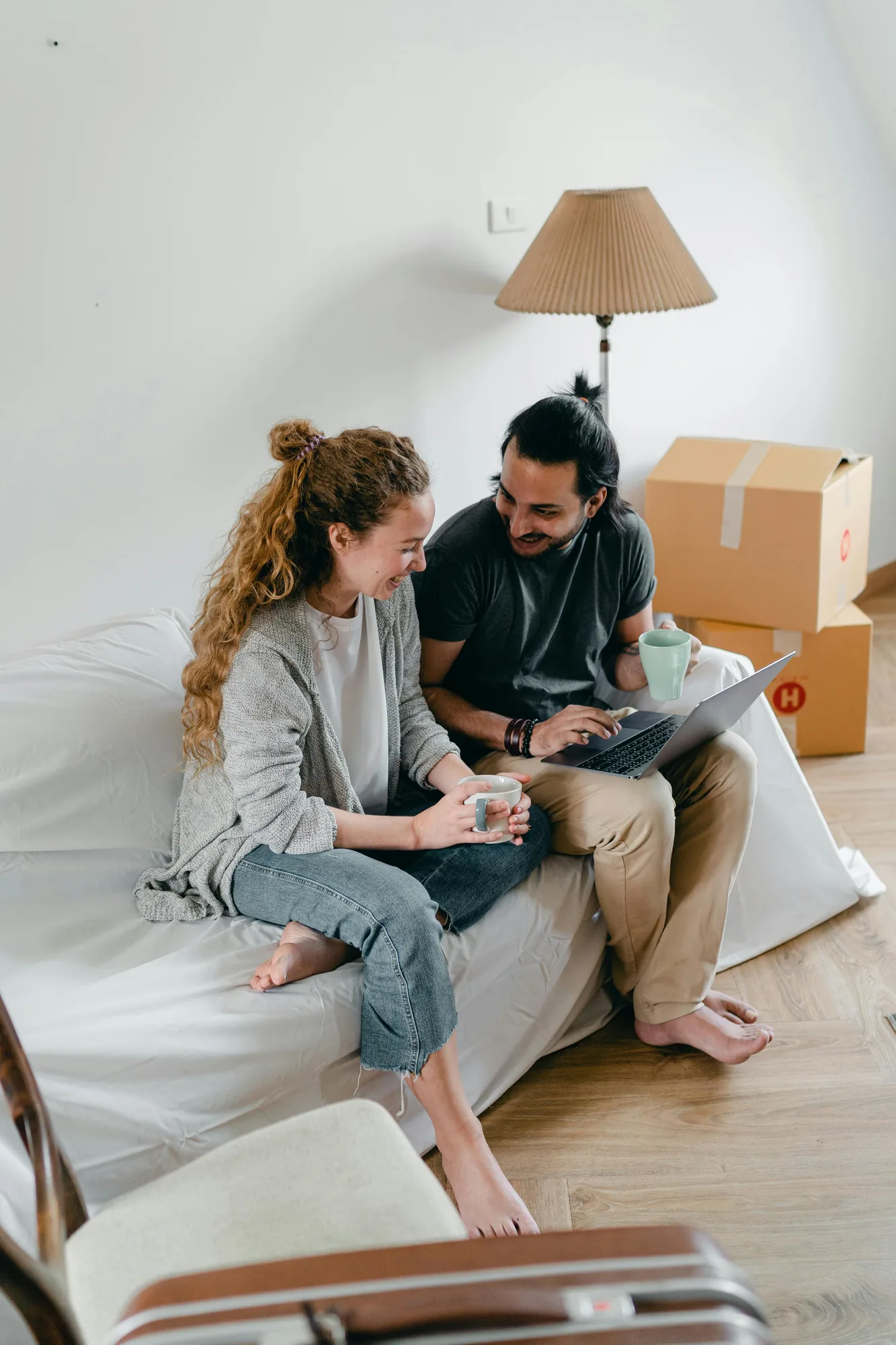 Young couple sitting together with a laptop while moving home