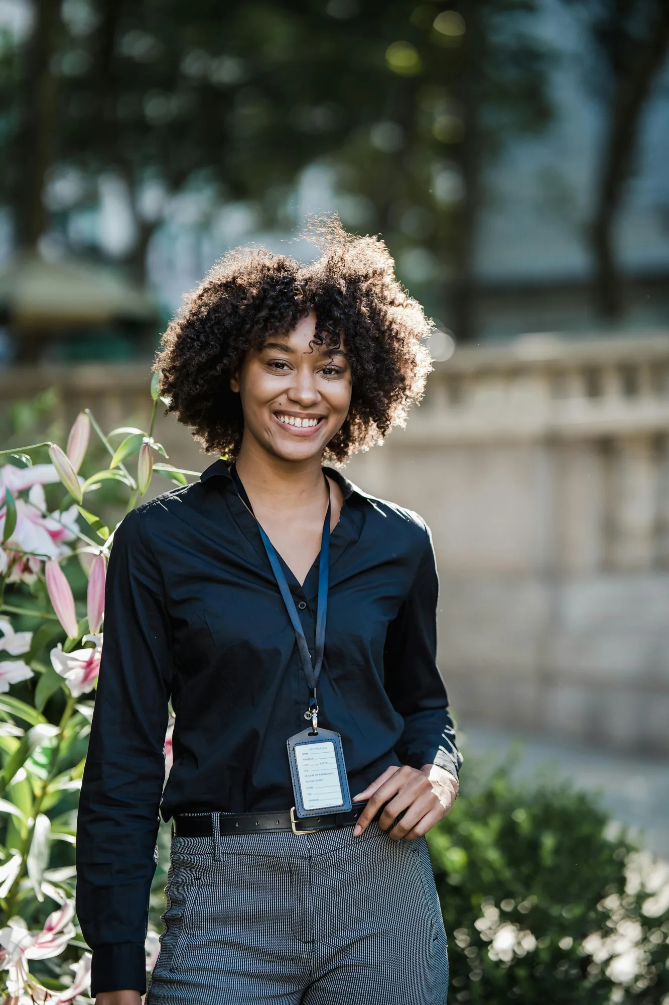 Smiling young professional outdoors wearing a work ID lanyard