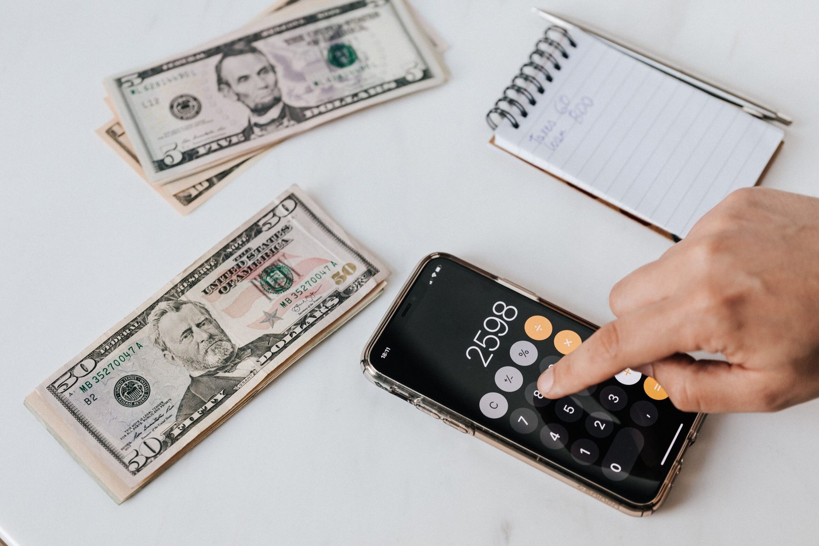 Dollar bills, a smartphone calculator and a notebook used to plan a budget with irregular income