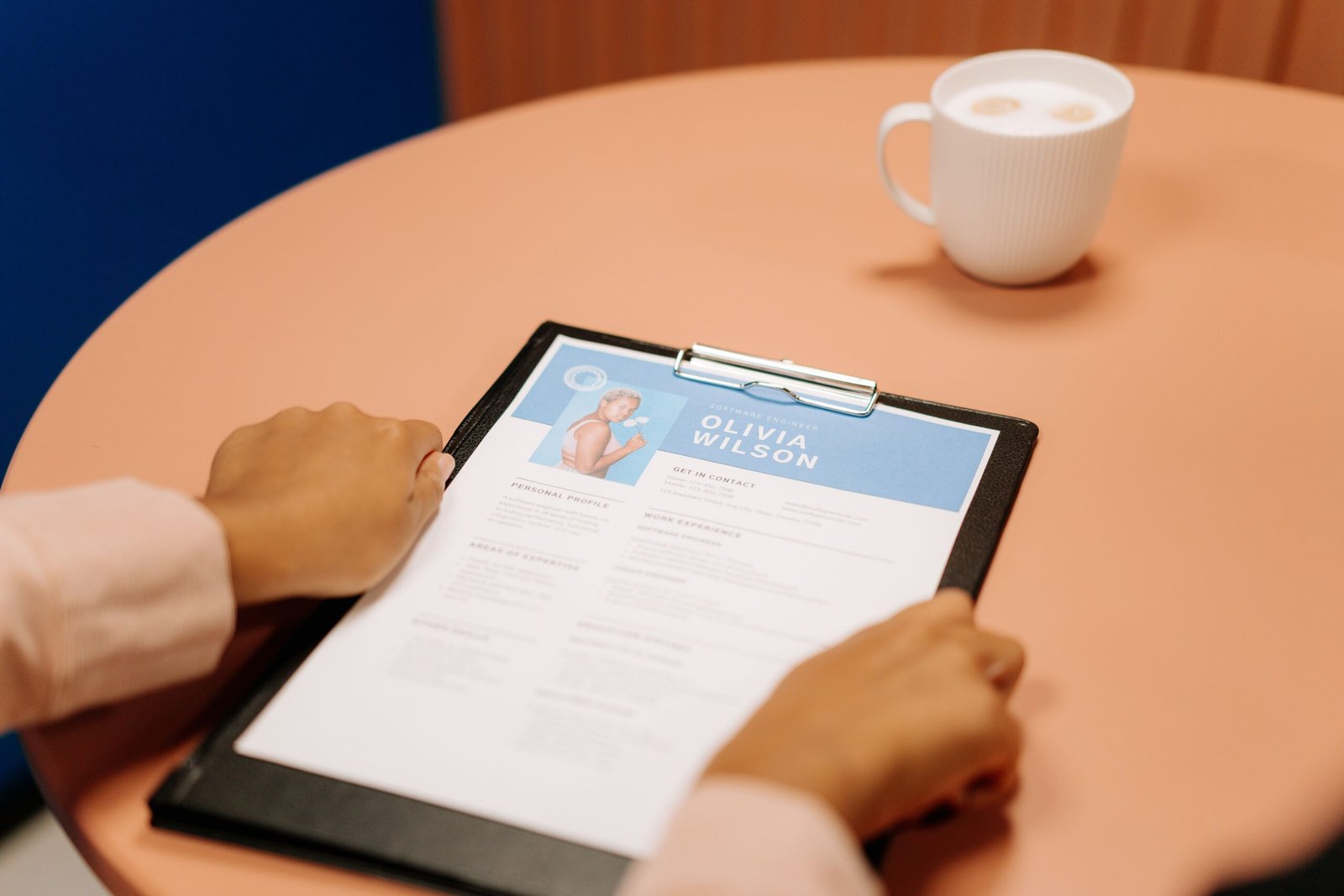 Person reviewing a printed resume on a clipboard at a table