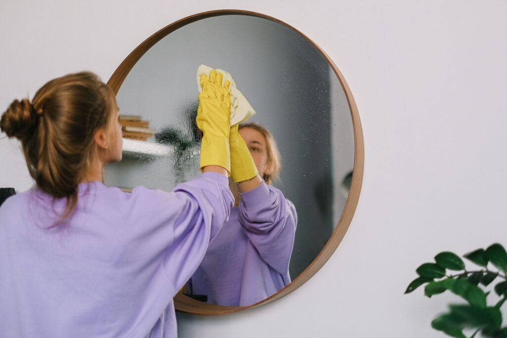 Young woman cleaning a round mirror as part of a simple weekly home management routine