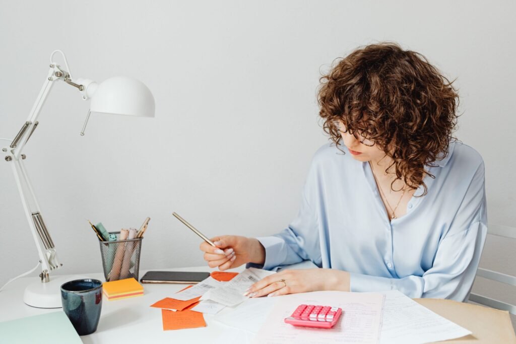 Young woman reviewing bills and planning how to save money fast on a low income at her desk