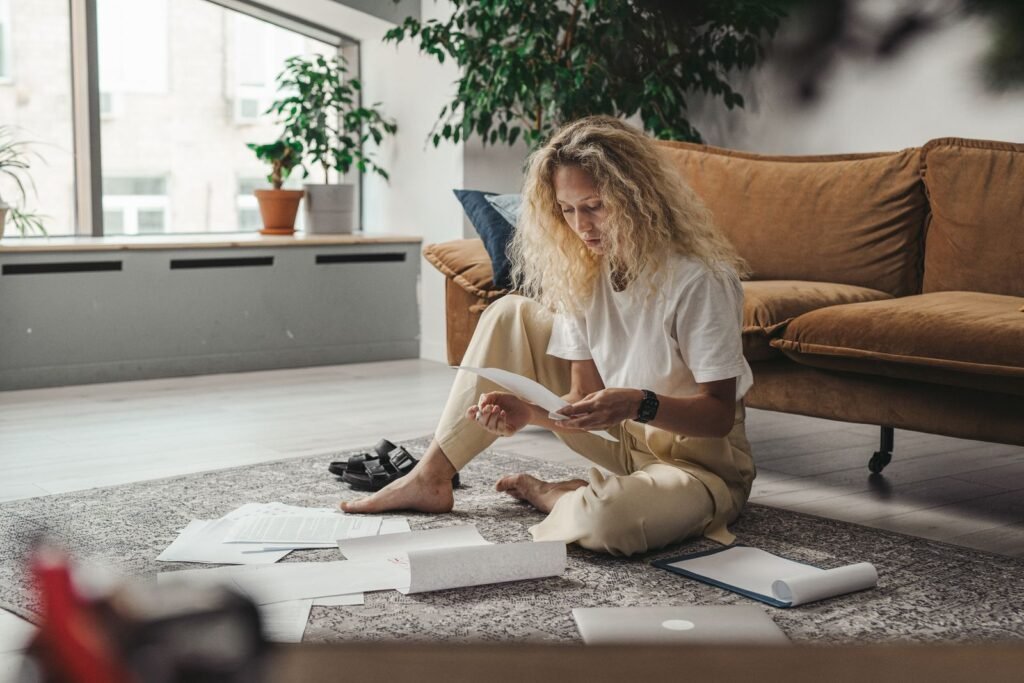 Young woman sitting on the floor at home while reviewing paperwork
