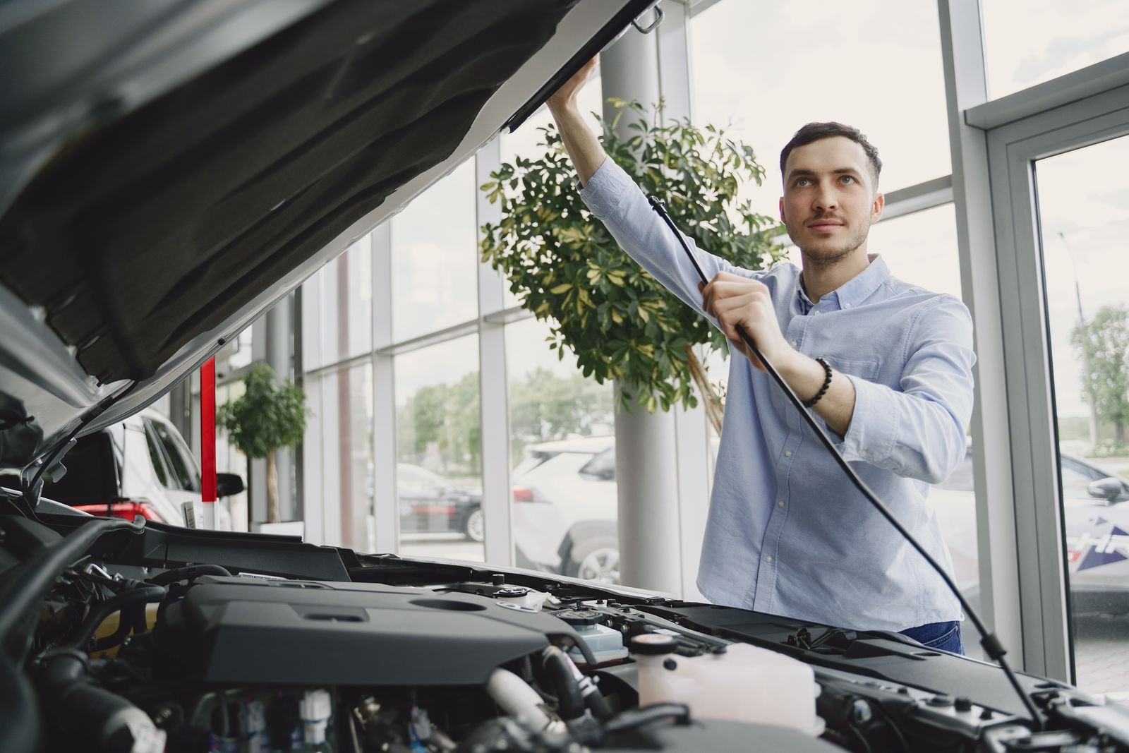 Young mechanic checking a car engine in a bright repair shop