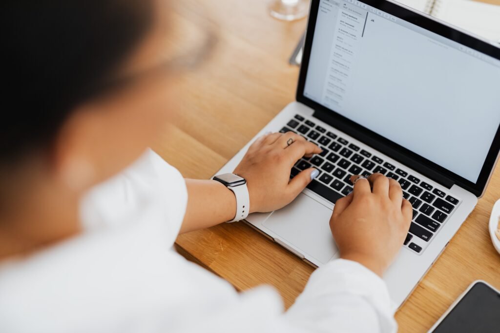 Close-up of hands typing on a laptop keyboard while writing a salary negotiation email